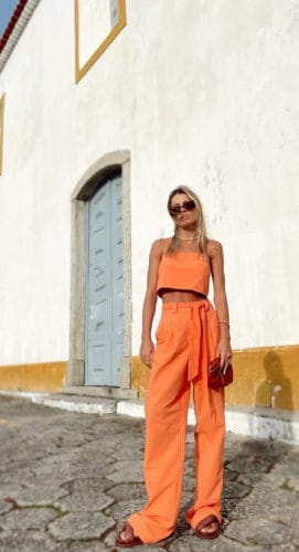 Mulher usando conjunto com calça e cropped na cor laranja.